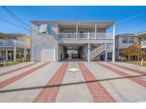 Charming beach house featuring covered parking, an outdoor staircase, and a spacious driveway with brick accents at 311 51St Ave. N, North Myrtle Beach, SC 29582