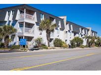 Beautiful condo building with balconies, lush greenery, and a glimpse of the nearby beach at 5001 N Ocean Blvd. # 1M, North Myrtle Beach, SC 29582