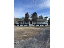 Charming one-story home with a large front porch, surrounded by trees and blue sky at 7030 Highway 701 North, Conway, SC 29526