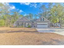 Charming single-story home featuring a two-car garage, well-manicured lawn, and inviting curb appeal at 87 Lake Trail, Pawleys Island, SC 29585