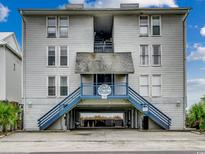 Three-story condo building featuring covered parking and stairway access, and the sign: 'The Sea Dollar' at 126 N Waccamaw Dr. # 203, Garden City Beach, SC 29576