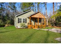 Charming home with a quaint front porch, surrounded by lush greenery and tall trees at 135 Oak Log Lake Rd., Conway, SC 29526