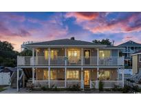 Charming two-story beach house featuring double balconies, inviting lighting, and beachy design elements under a colorful sky at 1420 S Ocean Blvd., North Myrtle Beach, SC 29582