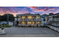 Charming two-story beach home with double decks and illuminated by string lights under a captivating sunset at 1420 S Ocean Blvd., North Myrtle Beach, SC 29582