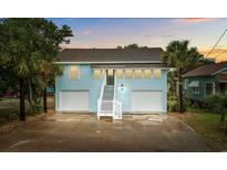 Charming two-story home with a ground-level garage, palm trees, and inviting staircase leading to the main entrance at 214 2Nd Ave. S, North Myrtle Beach, SC 29582