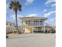 Inviting raised beach house featuring a charming exterior and a lush palm tree at 321 62Nd Ave. N, North Myrtle Beach, SC 29582