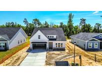 New construction home with attached garage featuring light gray siding, stone accents, and dark gray roof at 323 Dunlin Pl, Conway, SC 29526