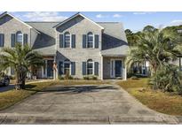 Charming townhome with brick facade, blue shutters, manicured lawn, and a spacious driveway at 3936 Tybre Downs Circle # 3936, Little River, SC 29566