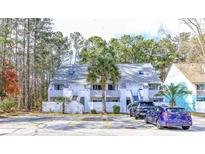Inviting exterior view of the condo featuring a well-maintained facade, ample parking, and mature trees at 401 Cambridge Circle # A1, Murrells Inlet, SC 29576