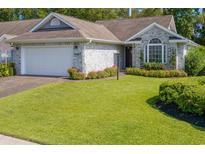 Charming one-story home featuring a well-manicured lawn, brick driveway, and appealing architectural details at 4856 Bermuda Way N, Myrtle Beach, SC 29577