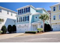 Charming three-story home with a two car garage, lush landscaping, and a blue exterior paint job at 4934 Salt Creek Ct., North Myrtle Beach, SC 29582