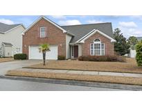 Charming brick home with attached two-car garage, well-kept lawn, and lush landscaping at 5077 Capulet Circle, Myrtle Beach, SC 29588