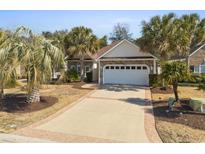 Charming single-story home featuring a stone facade, two-car garage, palm trees, and a patterned concrete driveway at 606 5Th Ave. S, North Myrtle Beach, SC 29582