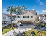 Inviting coastal home featuring elevated construction, a palm tree, and a spacious driveway at 919 Salt Pl., Murrells Inlet, SC 29576