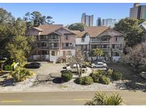This is an exterior shot of a condominium with a parking lot and well-kept landscaping near the building at 306 74Th Ave. N # 105, Myrtle Beach, SC 29572