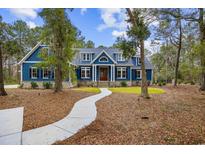 Stunning exterior of a blue two-story home with a winding pathway and lush landscaping at 341 Brickwell Ln., Pawleys Island, SC 29585