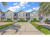 Charming townhome featuring a gray brick facade, blue shutters, well-manicured landscaping and concrete driveway at 4293 Parkway Ln. # 34, Little River, SC 29566