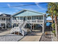 Inviting two-story raised beach home featuring a charming front porch and well-manicured landscaping at 4805 Lake Dr., North Myrtle Beach, SC 29582