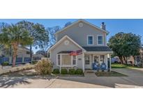 Charming two-story home with light gray siding, a covered porch, and an American flag waving above the bay window at 912 Tiffany Ln., North Myrtle Beach, SC 29582