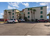 Oceanfront complex with beige stucco and green shutters accented by palm trees and paved parking at 105 S Ocean Blvd. # 108, North Myrtle Beach, SC 29582