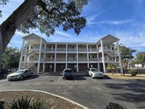 Three story condo building showing exterior walkways, brick facade, and ample parking at 1058 Sea Mountain Hwy. # 14-203, North Myrtle Beach, SC 29582