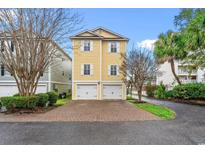 Charming yellow two-story home featuring a two-car garage and brick paver driveway at 1335 Hidden Harbor Rd., Myrtle Beach, SC 29577
