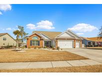 Charming single-story home with red brick and white siding, manicured lawn, and attached two-car garage at 1606 Lake Egret Dr., North Myrtle Beach, SC 29582