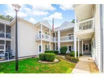 Well-maintained condo with green lawn, lush landscaping, and a charming white exterior at 2203 Sweetwater Blvd. # 2203, Murrells Inlet, SC 29576