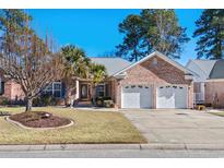 Charming brick home featuring an attached two-car garage, mature landscaping, and a well-manicured lawn at 3220 Hermitage Dr., Little River, SC 29566