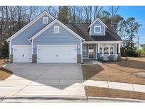 Charming light-blue home with a three-car garage and inviting front porch, showcasing curb appeal at 5501 Bristle Cone Ct., Myrtle Beach, SC 29577