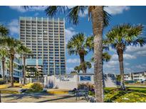 Ocean Forest Plaza condo building with lush landscaping, palm trees, and signage on a bright, sunny day at 5523 N Ocean Blvd. # 1513, Myrtle Beach, SC 29577
