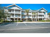 Exterior view of condo building with three stories, balconies, and parking lot at 5801 Oyster Catcher Dr. # 723, North Myrtle Beach, SC 29582