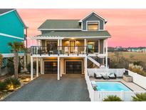 Stunning elevated coastal home featuring a private pool, black garage doors, and dual balconies at 604 Ocean Boulevard W, Holden Beach, NC 28462