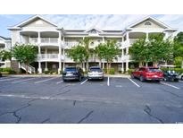 Exterior view of a condominium complex featuring multiple stories and ample parking spaces at 6203 Catalina Dr. # 1811, North Myrtle Beach, SC 29582