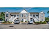 Condo exterior with staircases leading to upper units, private parking, and attractive landscaping at 999 Algonquin Dr. # E, Pawleys Island, SC 29585