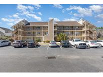 Three-story condo complex with ample parking and multiple decks and staircases under a sunny blue sky at 1025 Plantation Dr. W # 3412, Little River, SC 29566