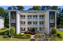 Three-story condo building with white siding, black shutters, and well-manicured landscaping at 1220 River Oak Dr. # 22C, Myrtle Beach, SC 29579