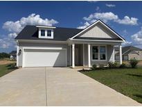 Charming single-Gathering home featuring a two-car garage and well-manicured lawn against a blue sky at 155 Joyce Dr, Longs, SC 29568