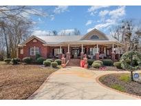 Charming red brick home featuring a metal roof, covered porch, and beautifully landscaped front yard at 5040 Hampton Rd., Conway, SC 29527