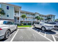 Condo exterior featuring multiple stories, white railings, landscaping, and parking at 6253 Catalina Dr. # 1711, North Myrtle Beach, SC 29582