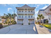 Charming coastal home featuring double porches, a light blue exterior, and a spacious driveway at 186 Cayman Loop, Pawleys Island, SC 29585
