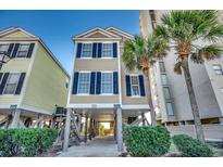 Charming beach house with blue shutters, raised on pilings, and lush tropical landscaping at 2000 N Waccamaw Dr., Garden City Beach, SC 29576
