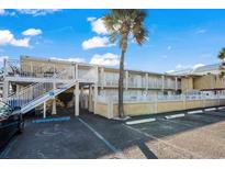 Charming two-story building with white railings, a palm tree, and accessible parking spaces at 2600 S Ocean Blvd. # 101, Myrtle Beach, SC 29577