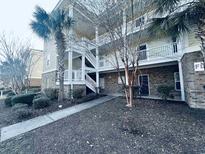 Inviting condo exterior with palm trees, white stairs, a walkway, and brick accents at 330 Kiskadee Loop # A, Conway, SC 29526
