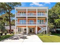 Stunning three-story beach house with white railings, covered parking, and an inviting stairway on a sunny day at 3304 Palm St., North Myrtle Beach, SC 29582