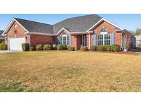 Charming brick home featuring a well-manicured front lawn and classic blue shutters at 3516 Queens Harbour Blvd., Myrtle Beach, SC 29588