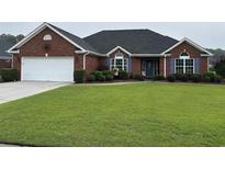 Charming one-story brick home with a well-manicured lawn and attached two-car garage at 3516 Queens Harbour Blvd., Myrtle Beach, SC 29588
