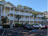 Bright, yellow condo building with multiple balconies, white railings, and palm trees offers a coastal living vibe at 4221 Hibiscus Dr. # 101, Little River, SC 29566