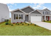 Charming single-story home featuring a well-manicured lawn and a two-car garage, with gray siding and black window shutters at 4517 East Coast Ln., Shallotte, NC 28470