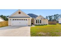 Charming single-story home featuring a two-car garage, manicured lawn and light yellow siding under a blue sky at 5026 Adrian Hwy., Conway, SC 29526